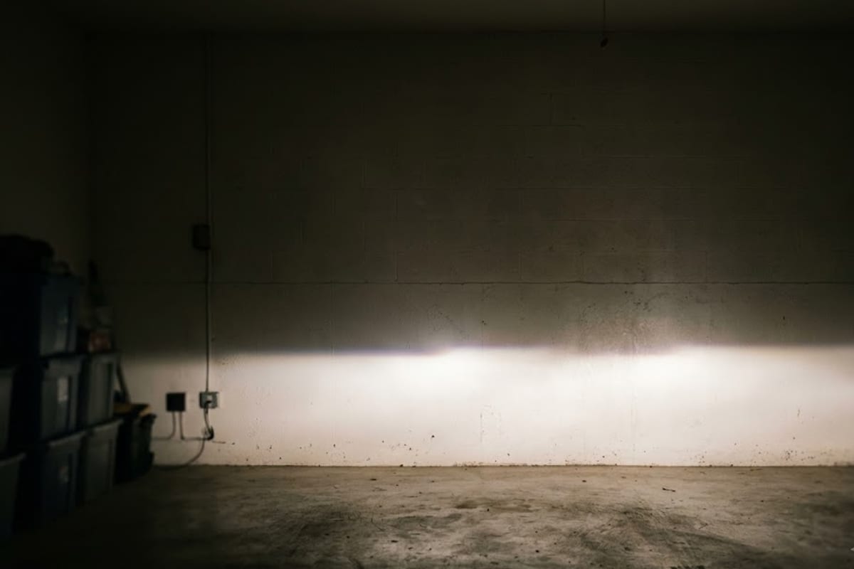 A low-beam cut-off line sitting unusually low on a garage wall